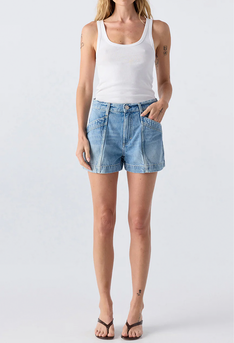 A woman wearing a white tank top and blue jean shorts. Taken on a white background.