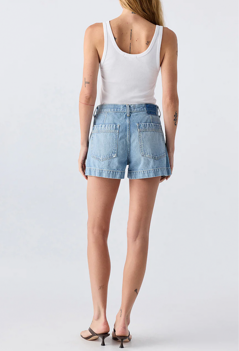 The back of a woman wearing a white tank top and blue jean shorts. Taken on a white background.