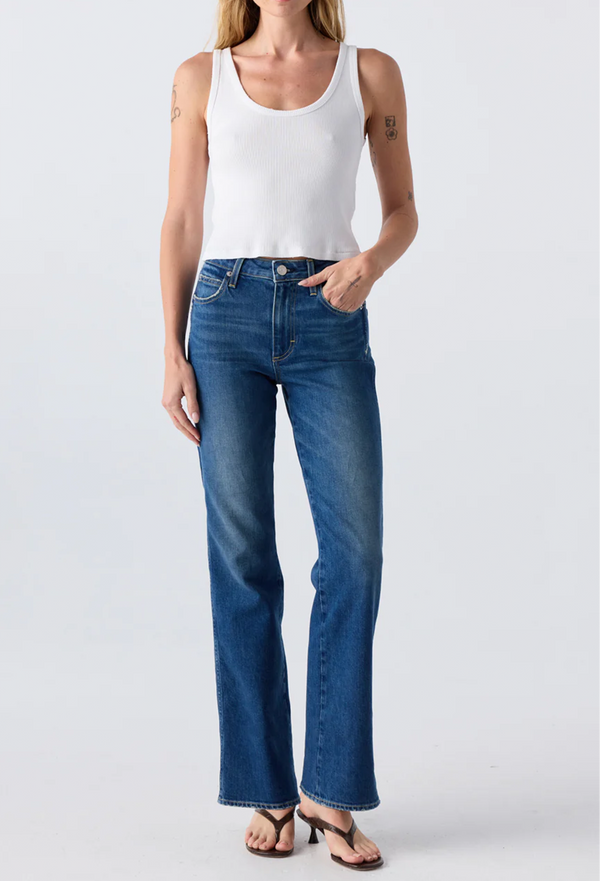 Close up of a woman wearing a white tank top and blue jeans. Taken on a white background.