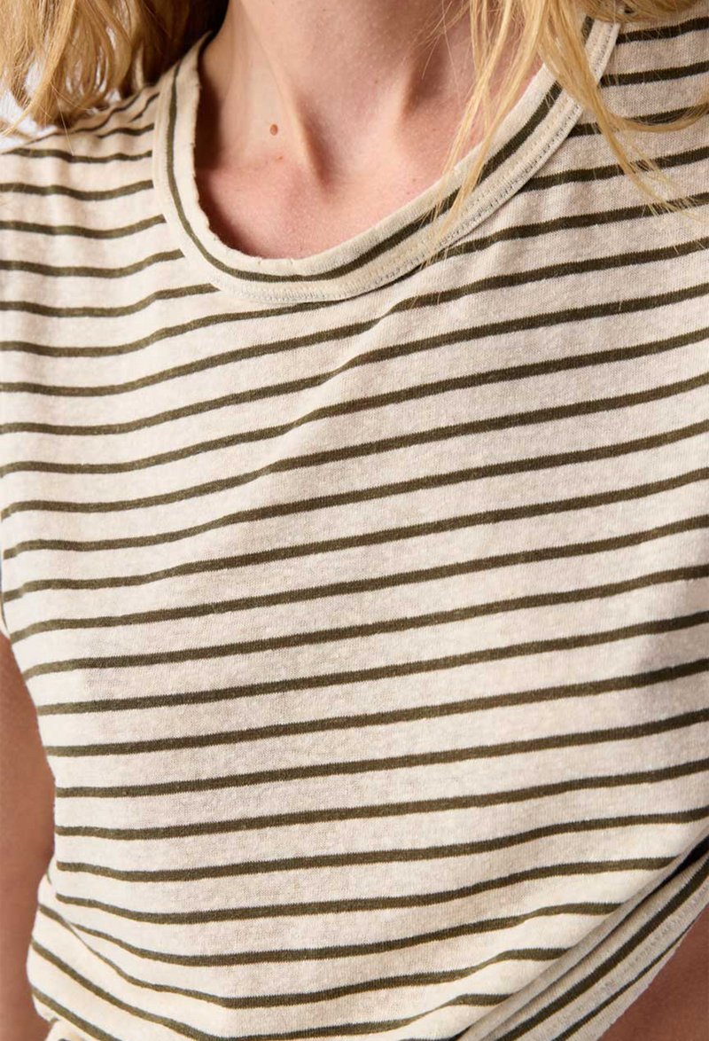 Close up of a woman wearing an off white sleeveless tee with brown stripes. 