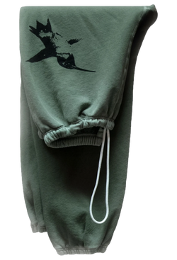 A pair of folded green sweatpants with a black screen printed bird on the thigh and a drawstring. Transparent background.