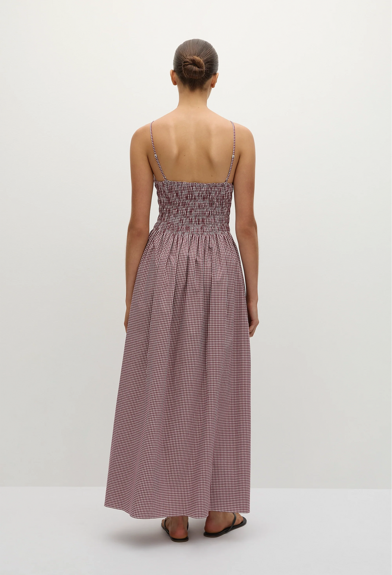 The back of a woman wearing a red and white gingham printed midi dress with a shirred bodice and spaghetti straps. Taken on a white background.