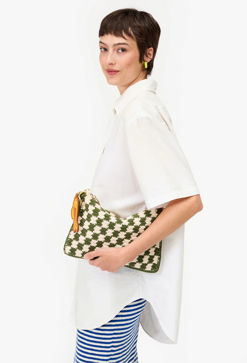 Woman carrying green and white checkered clutch bag. Taken on a white background.