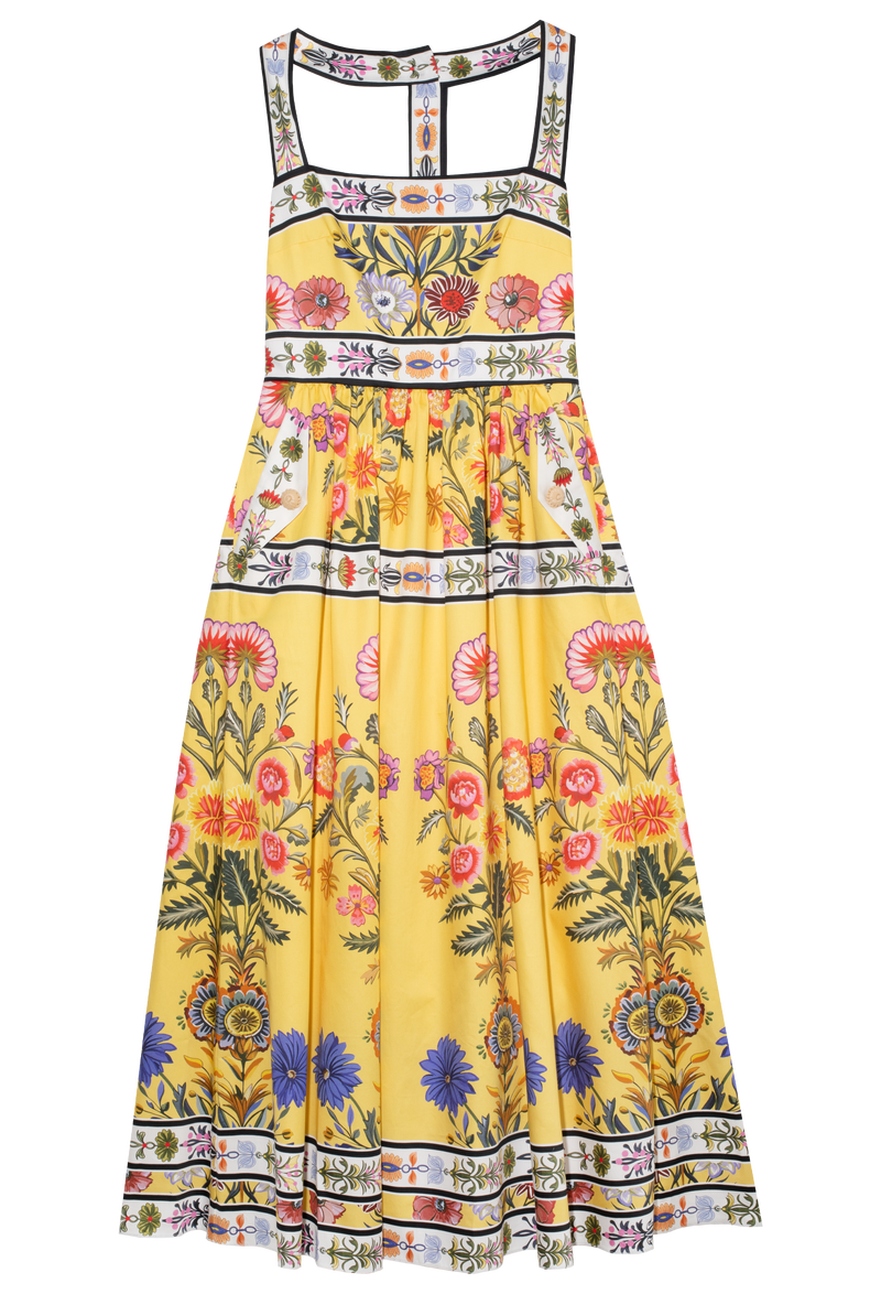 Yellow t-strap long dress with pink, white, black, purple printed flower detail. Set against a checkered background.