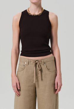 Model wears form fitting ribbed racerback chocolate brown tank. She also wears khaki drawstring pants, and a gold necklace. White background.