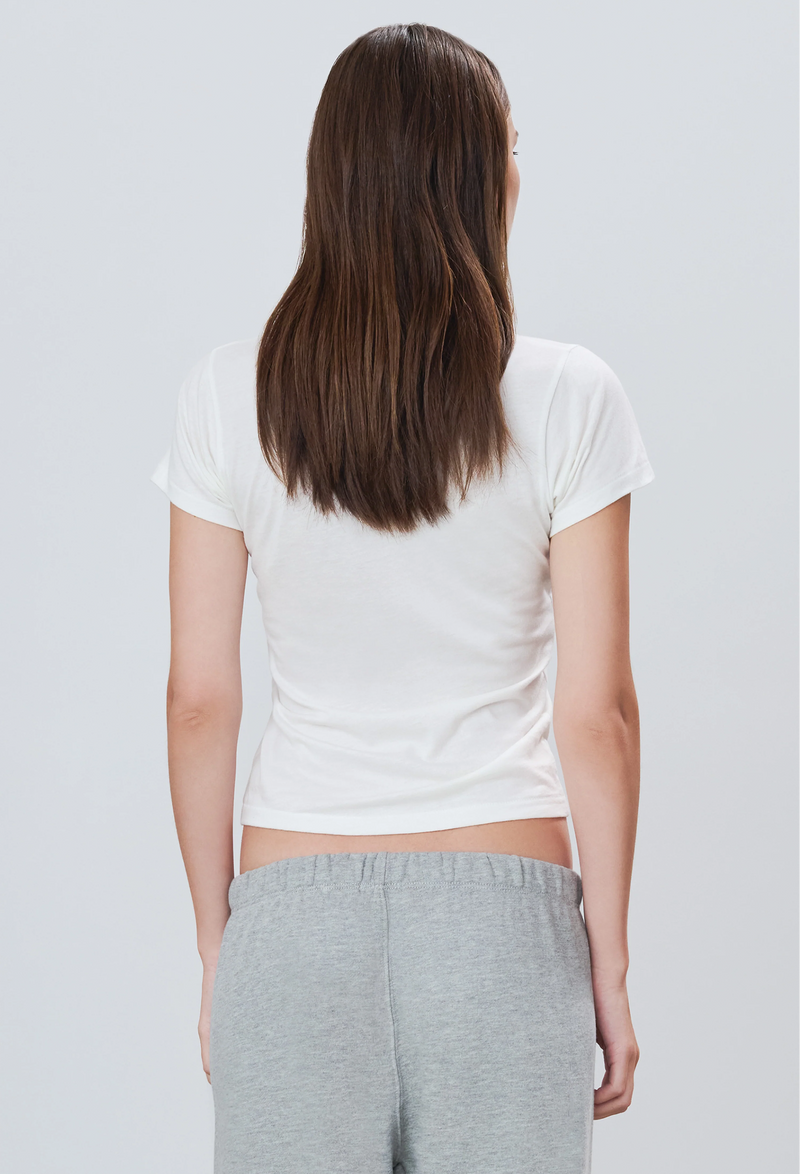 the back of a woman wearing a white short sleeve fitted t-shirt and grey sweatpants. white background.