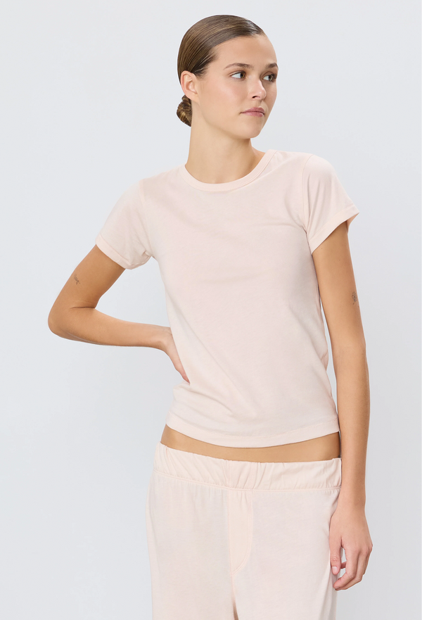 a woman wearing a light pink short sleeve fitted t-shirt. white background.