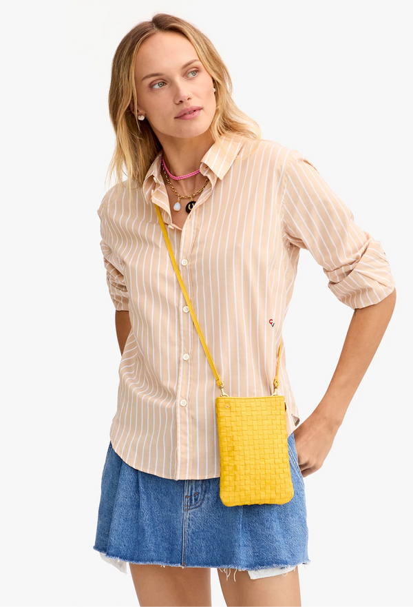 a woman with a crossbody yellow woven phone pouch bag. white background