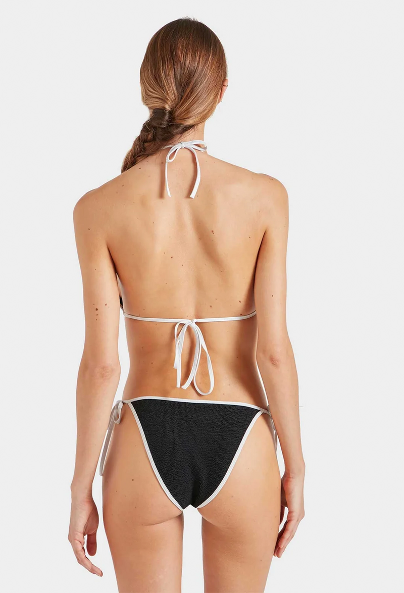the back of a woman wearing a black triangle string bikini with white borders. white background.
