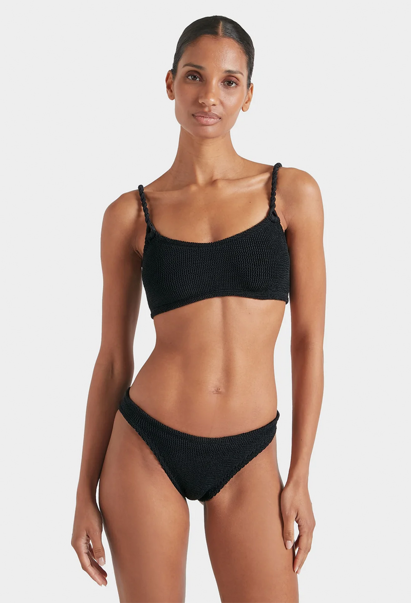 a woman wearing a black bikini with crinkle fabric. white background.