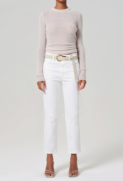 a woman wearing a sweater and slim straight leg white jeans cropped at the ankle. white background.