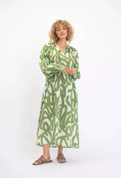 a woman wearing a white midi long sleeve button v-neck dress with a green scribble design. white background.