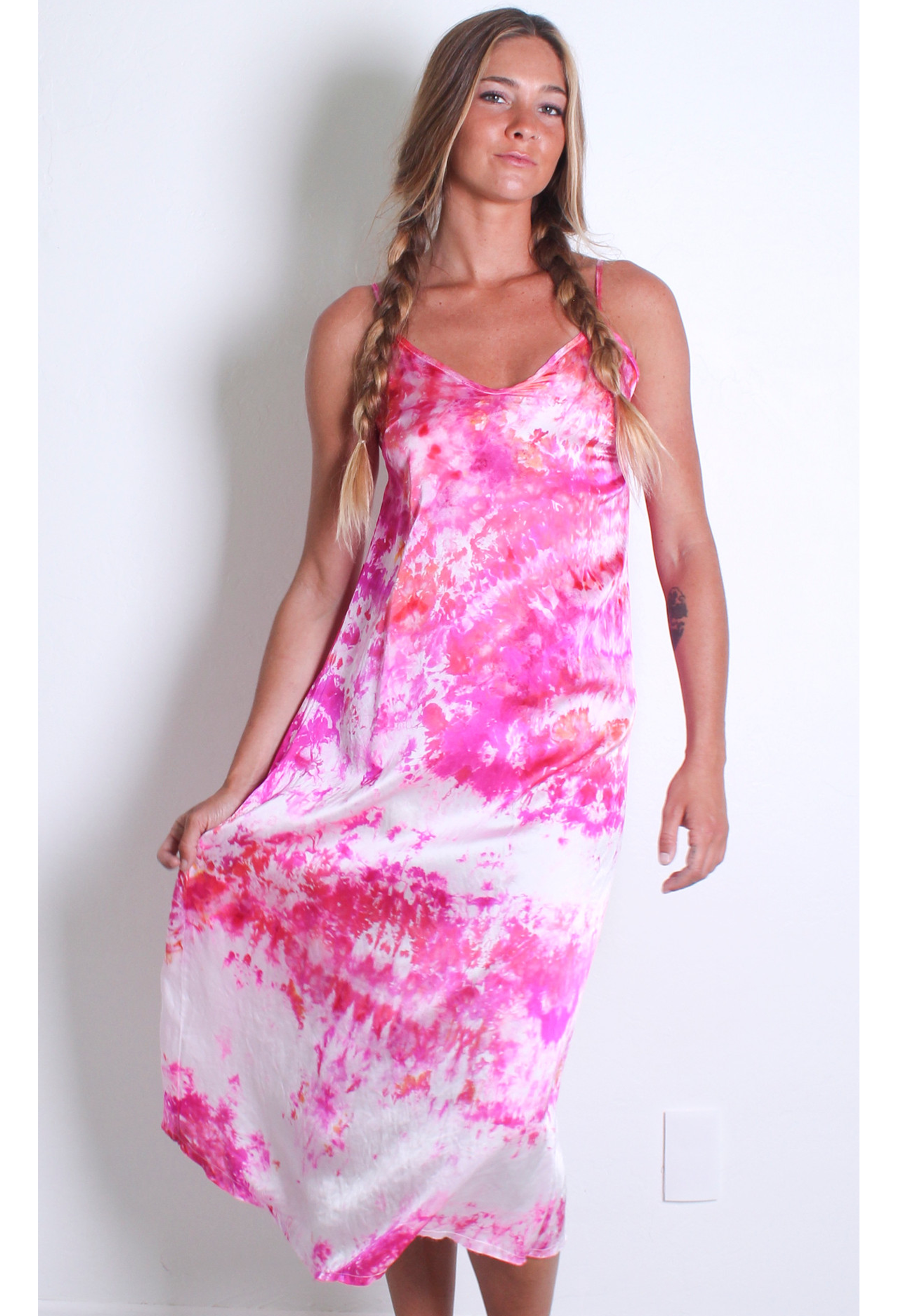 a woman in front of a white wall wearing a pink and white tie dyed midi slip dress.