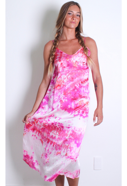 a woman in front of a white wall wearing a pink and white tie dyed midi slip dress.