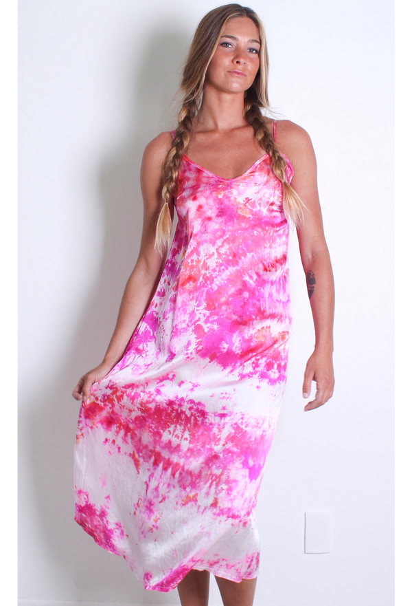 a woman in front of a white wall wearing a pink and white tie dyed midi slip dress.