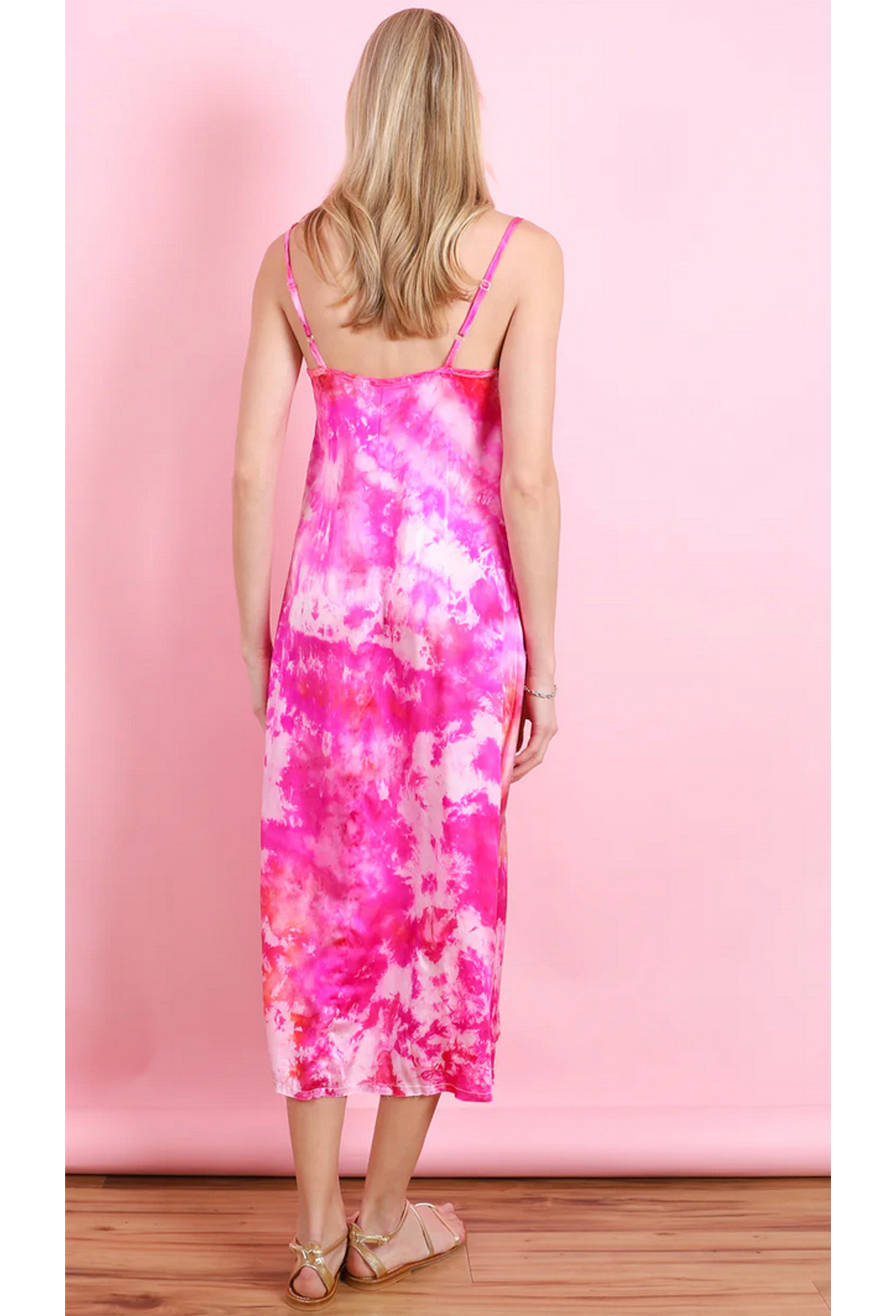 the back of a woman in front of a pink backdrop wearing a pink and white tie dyed midi slip dress.