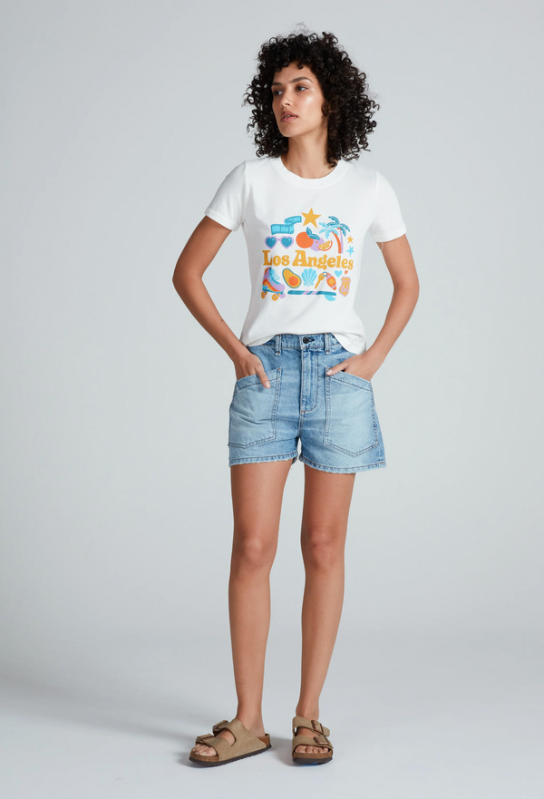 a woman wearing a white graphic t-shirt and light denim shorts with two large patch pockets. white background.