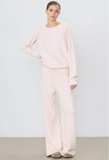 a woman wearing a light pink wide leg drawstring sweatpant and matching sweatshirt. white background.