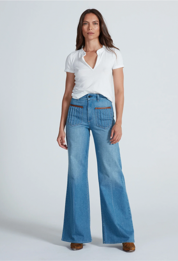 a model wearing a v-neck mock henley t-shirt with jeans. white background.