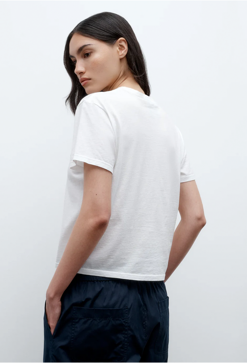 the back of a model wearing a white t-shirt and blue pants. white background.