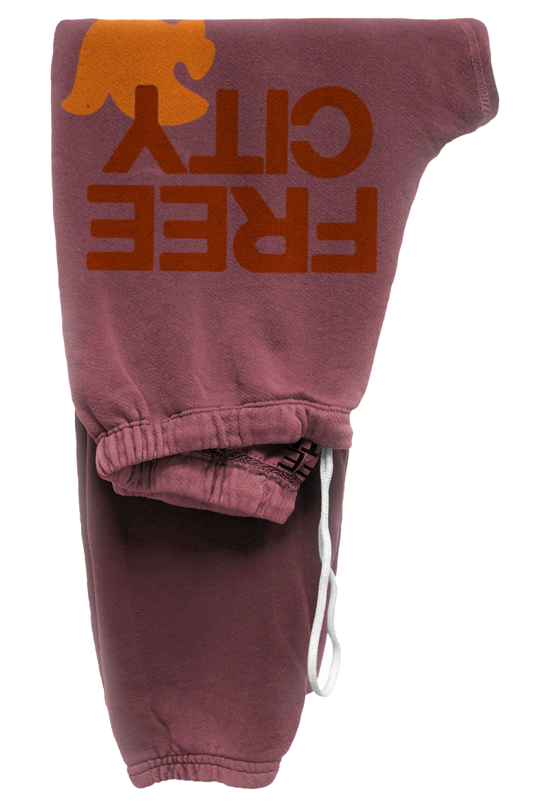 mauve sweatpant with classic "FREECITY" print in deep orange and tonal light orange "FREECITYDOVE," covered elastic waist and pull drawcord. transparent background.