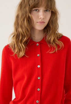a model wearing a red button down cashmere cardigan with a collar. white background