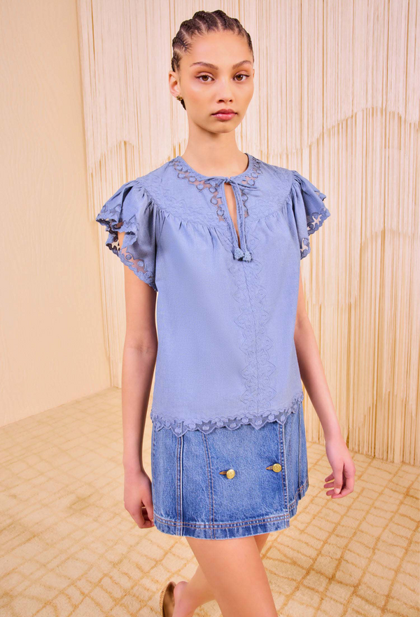 A model wearing a blue flutter sleeve top with tulle applique and a front necktie. transparent background. 