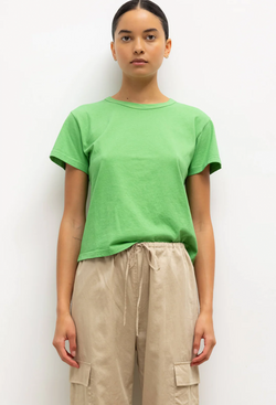 a model wearing a bright green short sleeve t-shirt and beige pants. white background.