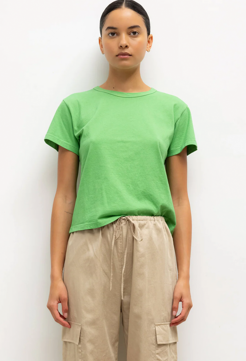 a model wearing a bright green short sleeve t-shirt and beige pants. white background.
