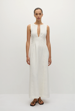 a model wearing a sleeveless deep v-neck white maxi dress with a fitted bodice and slightly flared skirt. white background.