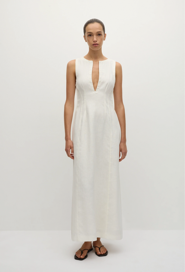 a model wearing a sleeveless deep v-neck white maxi dress with a fitted bodice and slightly flared skirt. white background.
