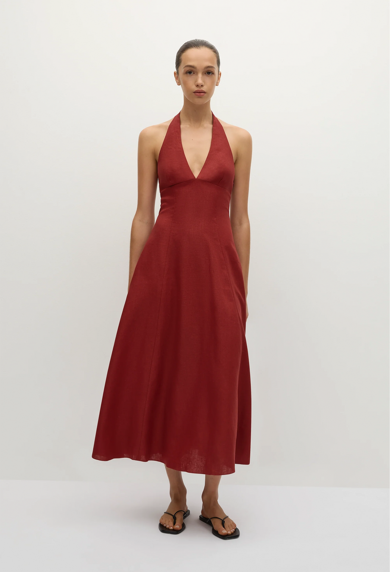a model wearing a red deep v halter neck midi dress. white background.