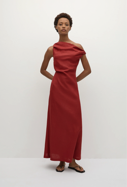 a model wearing a one-shoulder linen red maxi dress with one off the shoulder strap. white background.