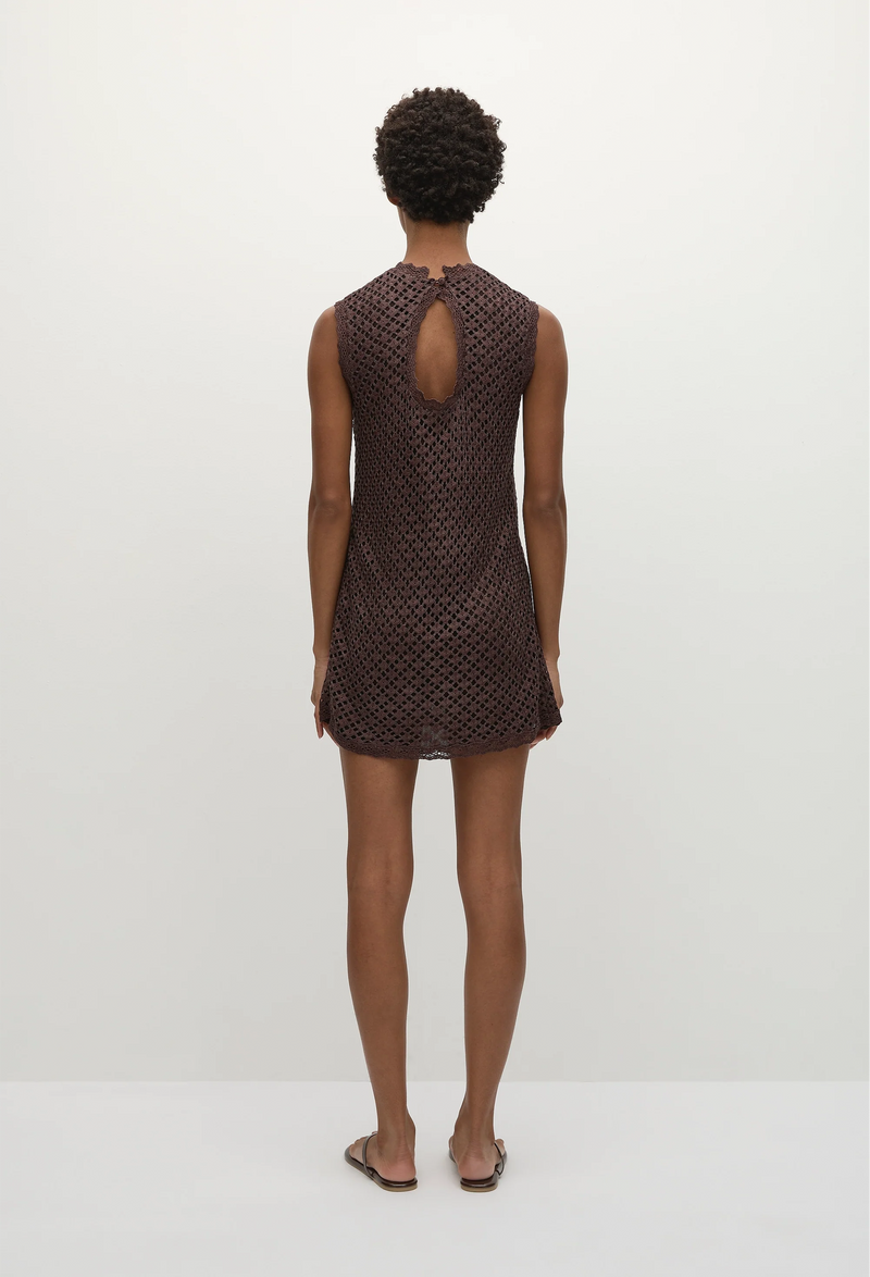 the back of a model wearing a brown sleeveless mini dress with a spectre lace fabrication. white background.