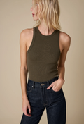 a model wearing an olive high neck racerback ribbed tank top and jeans. beige background