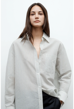 a model wearing an oversized white and dark green pinstripe collared button down shirt. white background