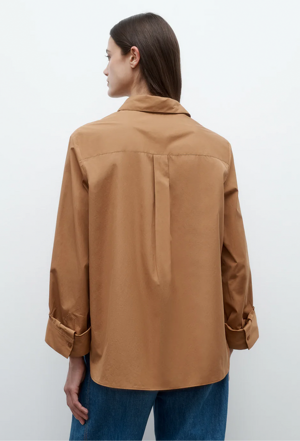 the back of a model wearing a caramel brown button up long sleeve shirt with jeans. white background.