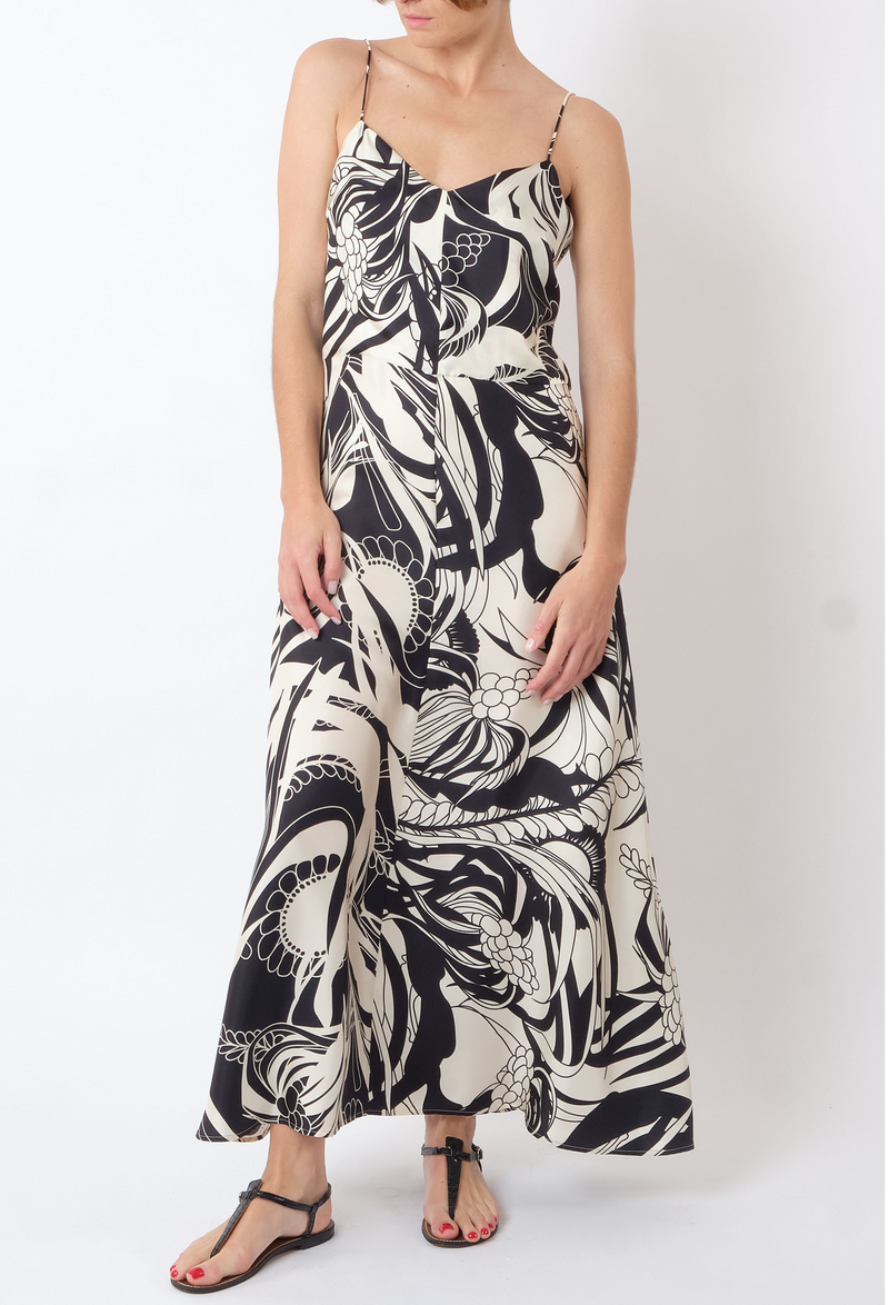 a model wearing a black and white v-neck spaghetti strap midi dress with a coral print all over. white background.
