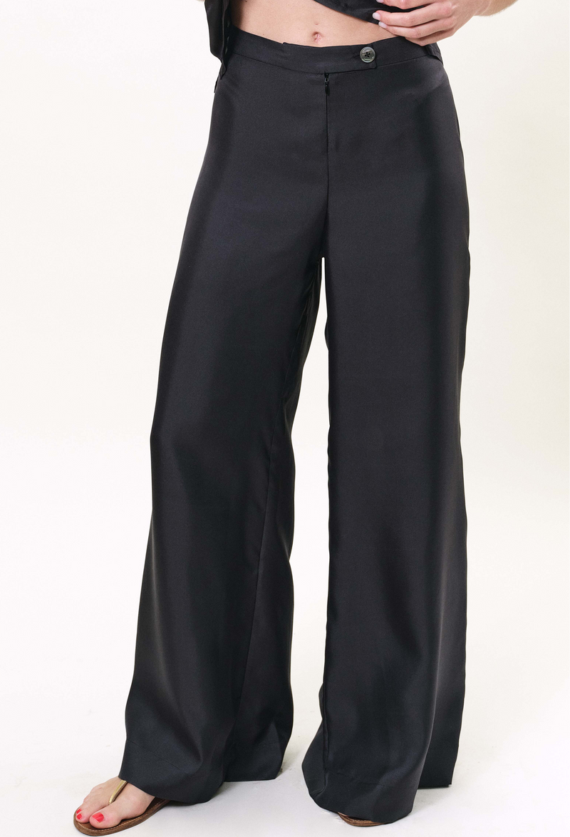 a model wearing a pair of zip-up black pants. white background.