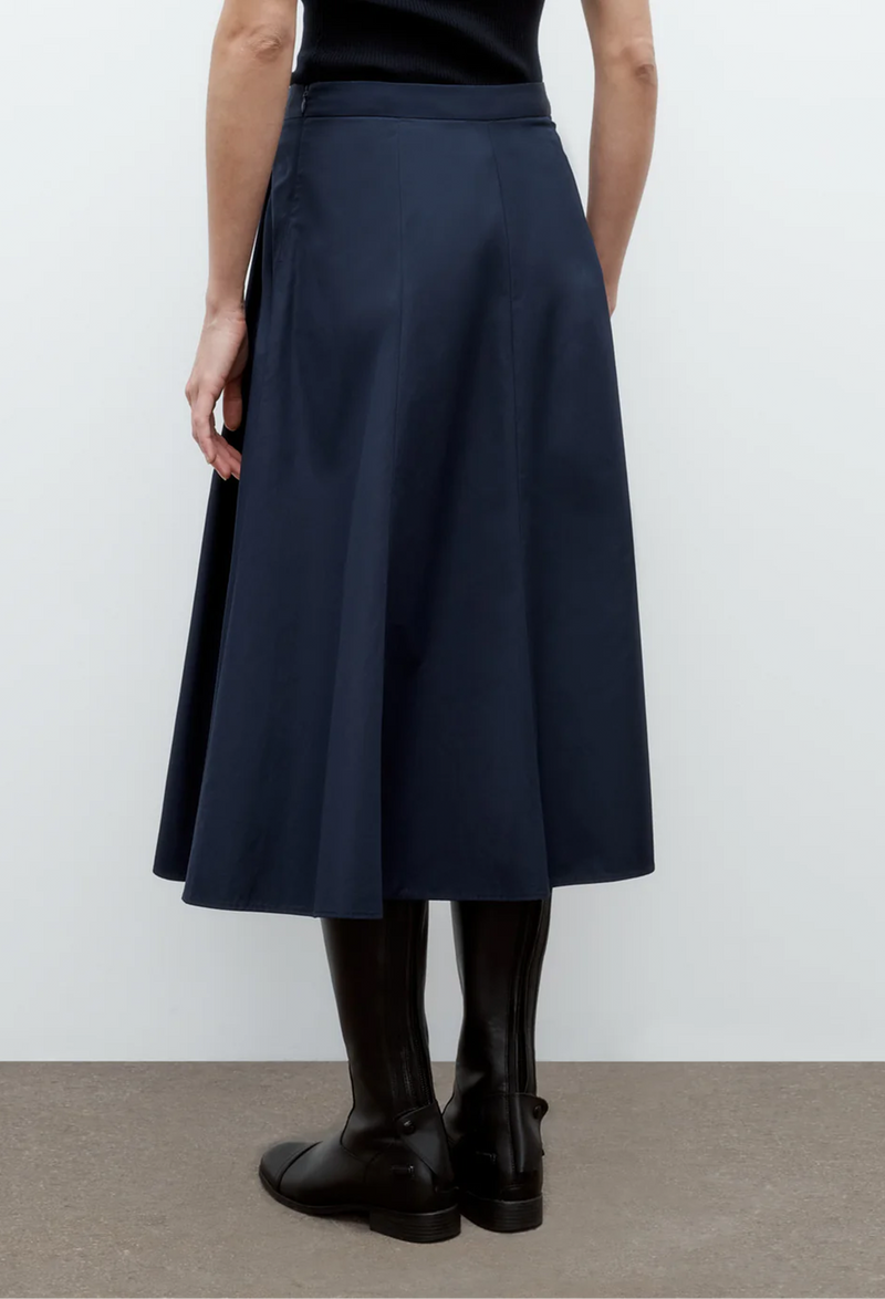 the back of a model wearing a blue tank top and a navy midi skirt with pleats. white background.
