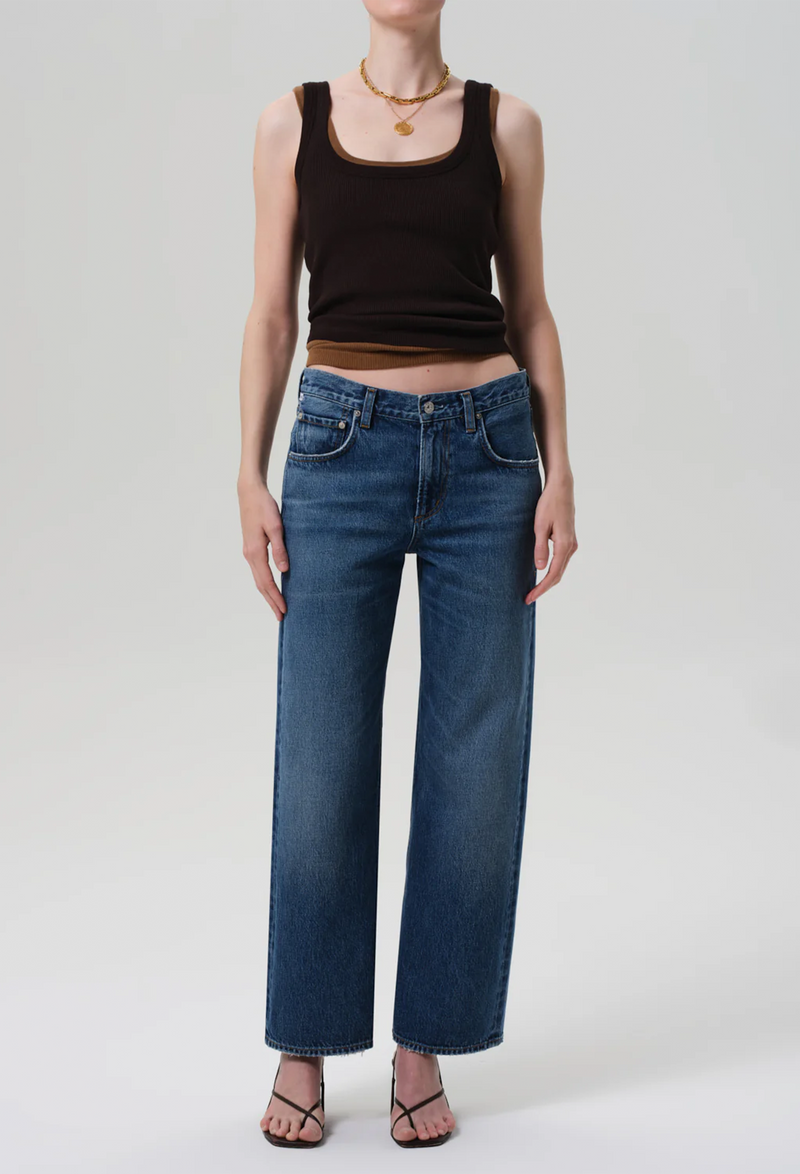 a model wearing brown tank tops and straight blue jeans on a white background