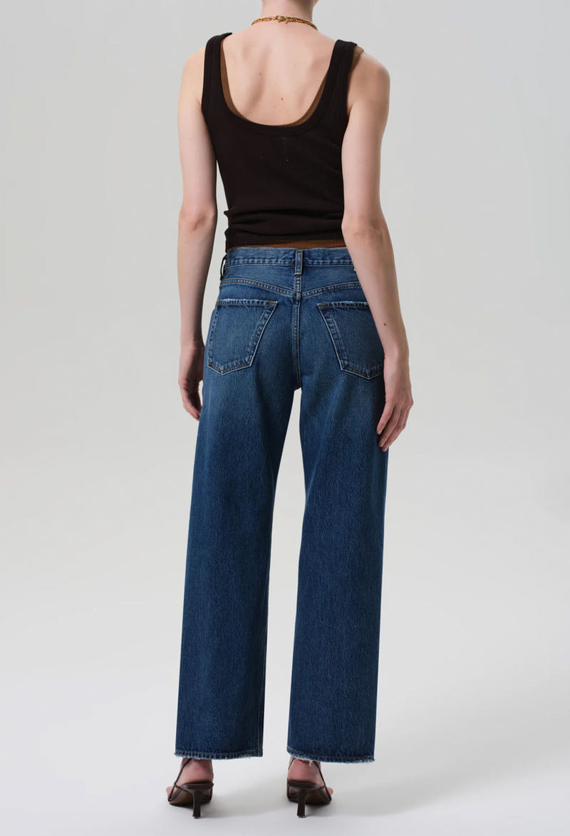 the back of a model wearing brown tank tops and straight blue jeans on a white background