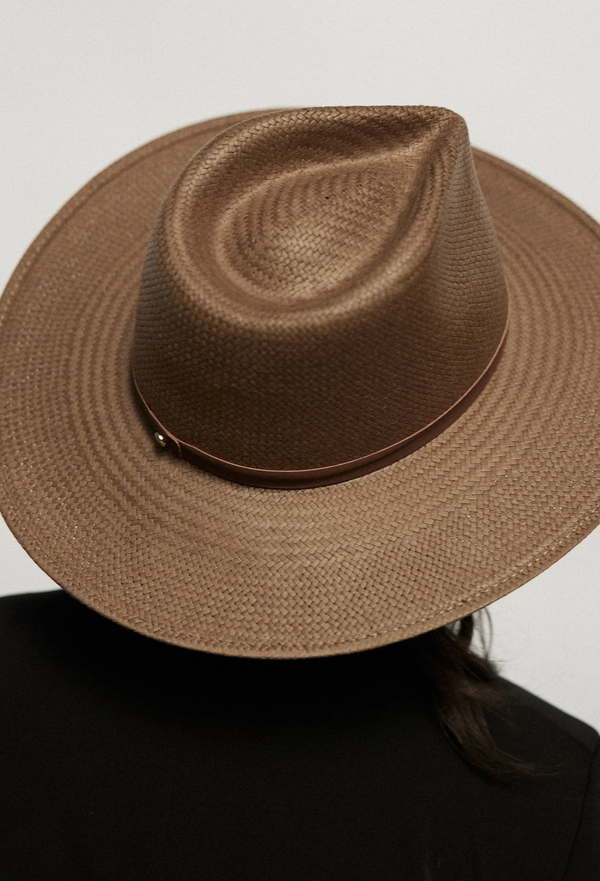 Brown straw hat worn by a person against a white background