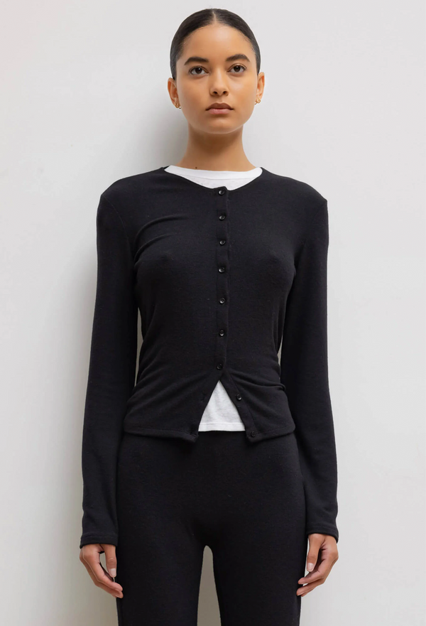 model wearing a black cardigan and leggings on a white background.