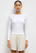 a model wearing a fitted white long sleeve tee and shorts on a white background.