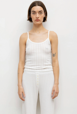 model wearing a white pointelle tank top and pants against a white background