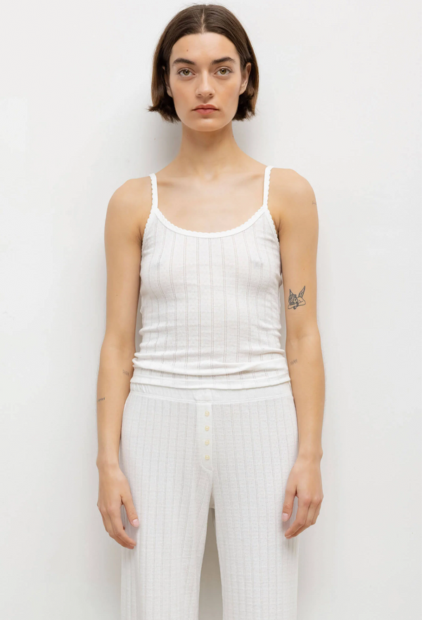 model wearing a white pointelle tank top and pants against a white background