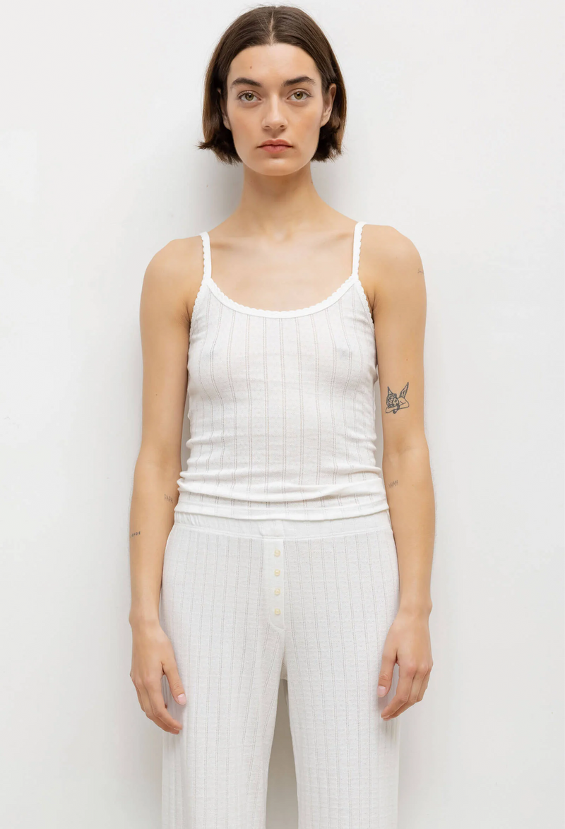 model wearing a white pointelle tank top and pants against a white background