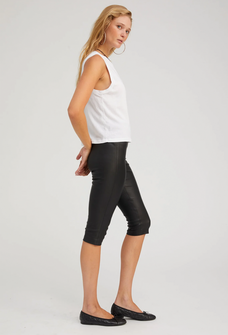 Woman wearing a white sleeveless top and black capri pants on a white background