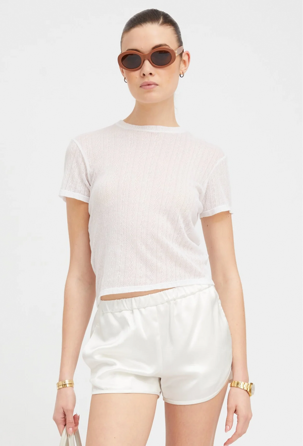 Person wearing a white t-shirt and shorts set with sunglasses on a white background